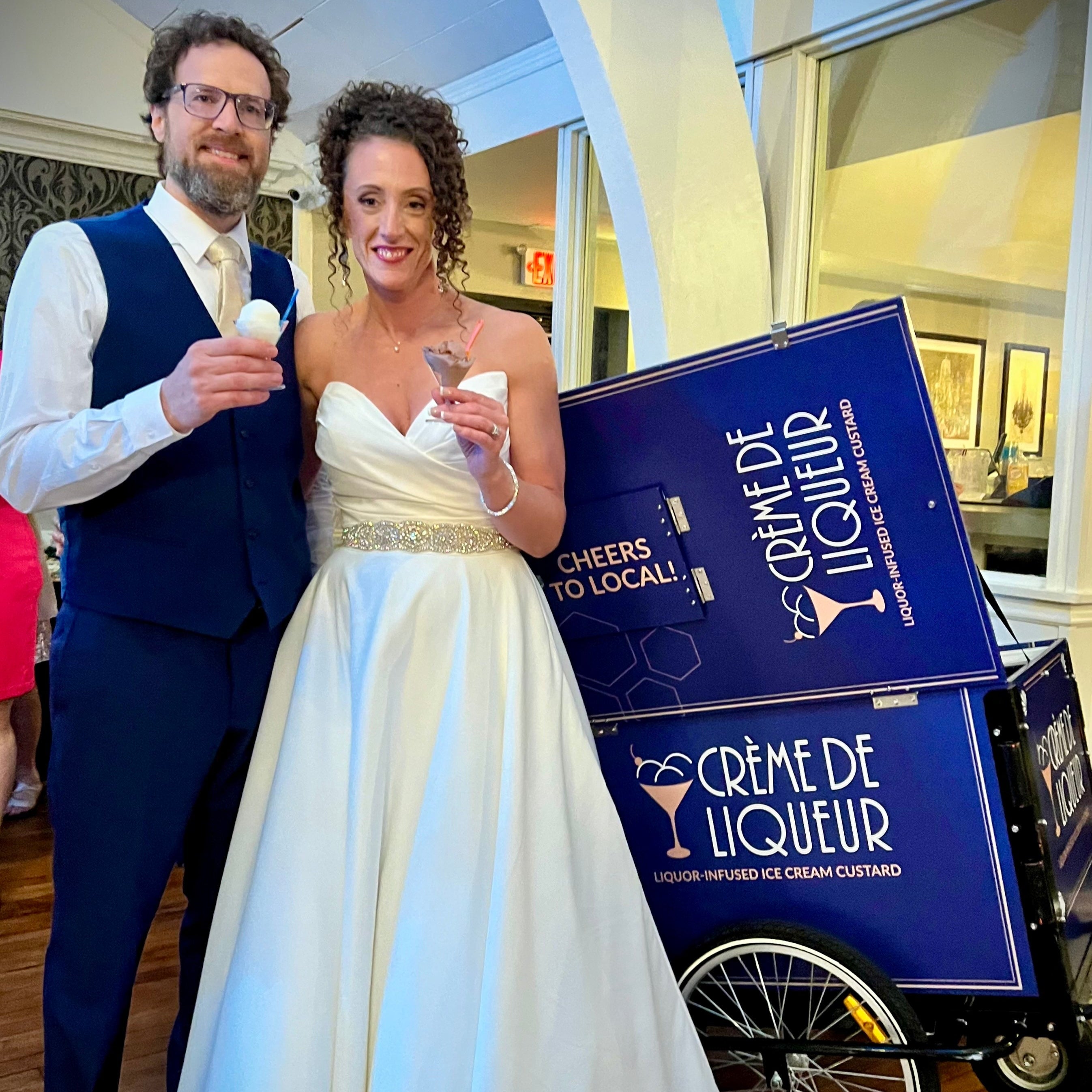 Bride and groom standing in front of Crème de Liqueur Ice Cream Cart
